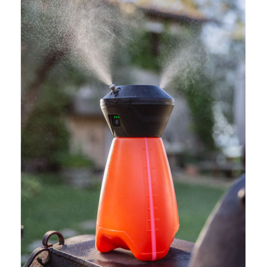 Geyser Nebulizzatore Mini da 2 litri in funzione, con spruzzo visibile e giardino sullo sfondo