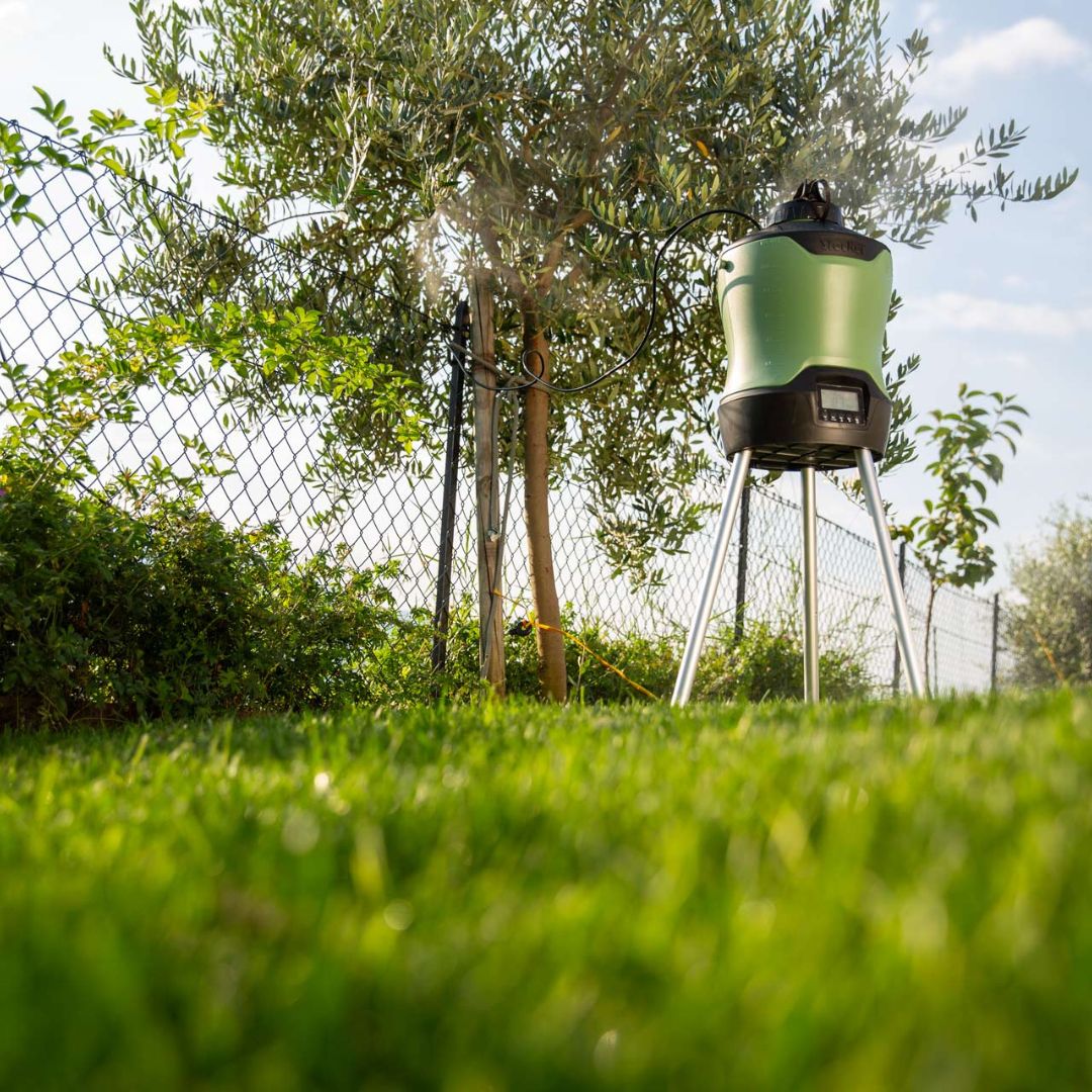 Nebulizzatore Geyser da 12 litri in funzione su prato, accanto a un albero e recinzione con ugelli attivi