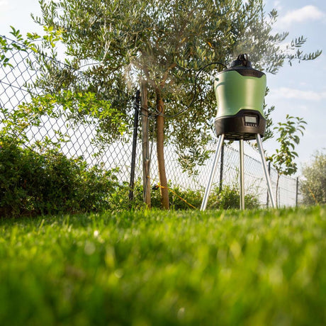 Nebulizzatore Geyser da 12 litri in funzione su prato, accanto a un albero e recinzione con ugelli attivi