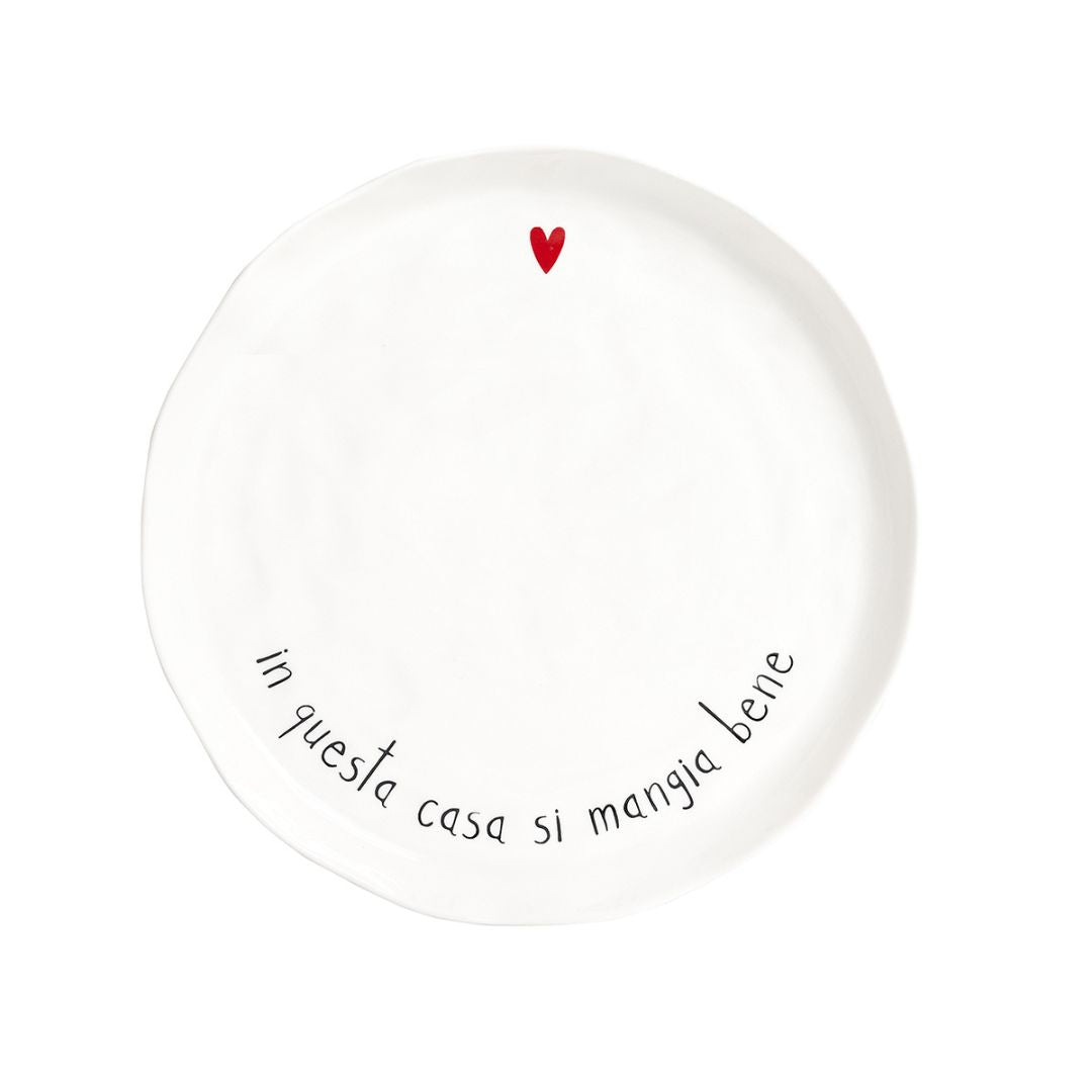 Piatto piano in grès con scritta nera "in questa casa si mangia bene" e cuoricino rosso.