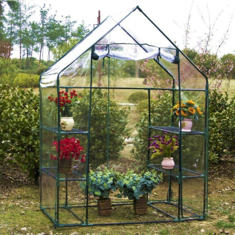 Serra con telo trasparente e ripiani, visibili piante e fiori. Struttura stabile, ideale per coltivare in sicurezza.