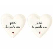Set di due piattini in grès a forma di cuore con scritta nera "goditi le piccole cose" e cuoricino rosso.