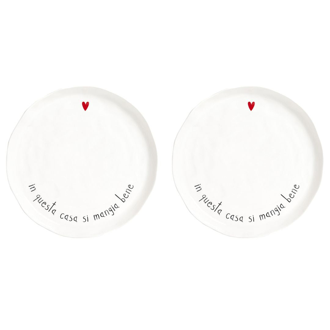 Set di due piatti piani in grès con scritta nera "in questa casa si mangia bene" e cuoricino rosso.
