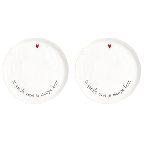 Set di due piatti piani in grès con scritta nera "in questa casa si mangia bene" e cuoricino rosso.