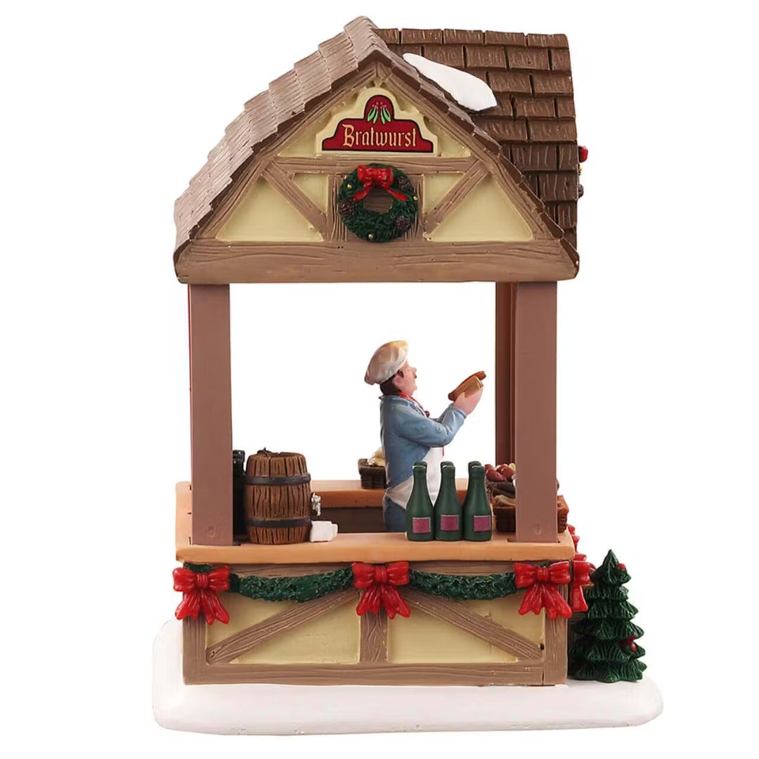 Vista laterale della bancarella natalizia con venditore di bratwurst, decorazioni natalizie e prodotti esposti.