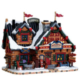 Chalet di montagna innevato con decorazioni natalizi e insegna “Snow Chalet Mountain Lodge”.