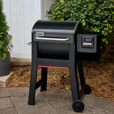 Barbecue a pellet Weber Smoque nero posizionato su una pavimentazione esterna