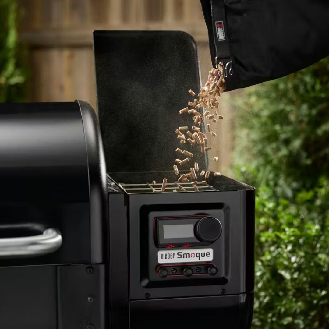 Dettaglio del serbatoio laterale del barbecue Weber Smoque durante il caricamento dei pellet