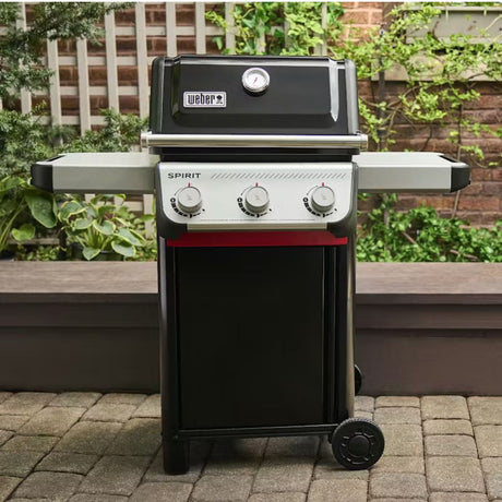 Barbecue a gas Weber Spirit E-310 nero posizionato su una pavimentazione esterna