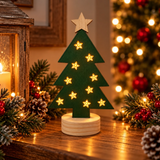 Albero natalizio verde luminoso in legno su un mobile, circondato da rami di abete, pigne e decorazioni rosse