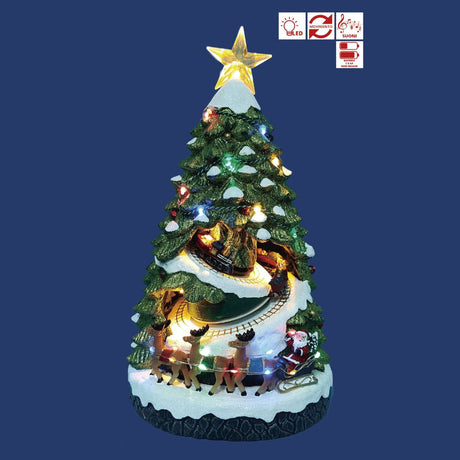 Albero di Natale decorativo illuminato con stella in cima, trenino che gira tra i rami e Babbo Natale con renne e slitta alla base su sfondo blu.