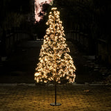 Albero decorativo alto 210 cm a LED bianco caldo acceso di notte con luci distribuite a ciuffi.