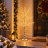 Albero spoglio innevato da 120 cm con LED bianco caldo, ambientato vicino alla porta d'ingresso con ghirlande e lanterne