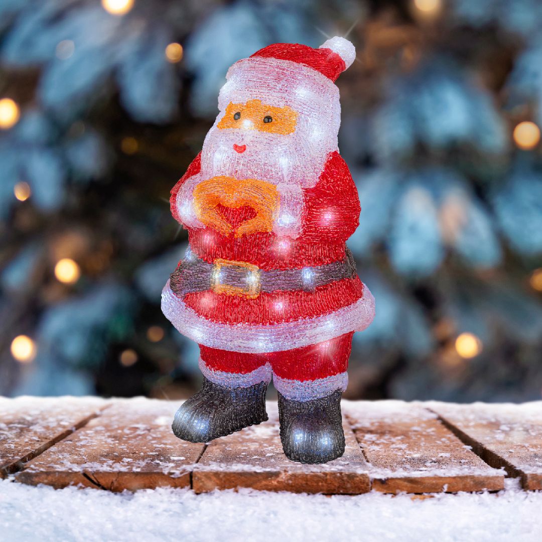 Babbo Natale luminoso in acrilico posizionato su base innevata, con sfondo di albero natalizio.