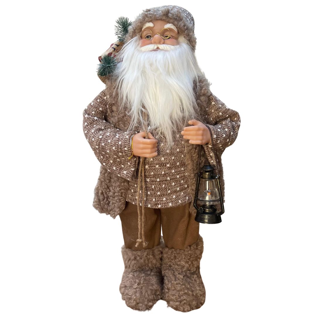 Figura decorativa di Babbo Natale in abiti beige con maglione lavorato, barba bianca, lanterna in mano e sacco con rami e pacchi regalo, alto 60cm. 