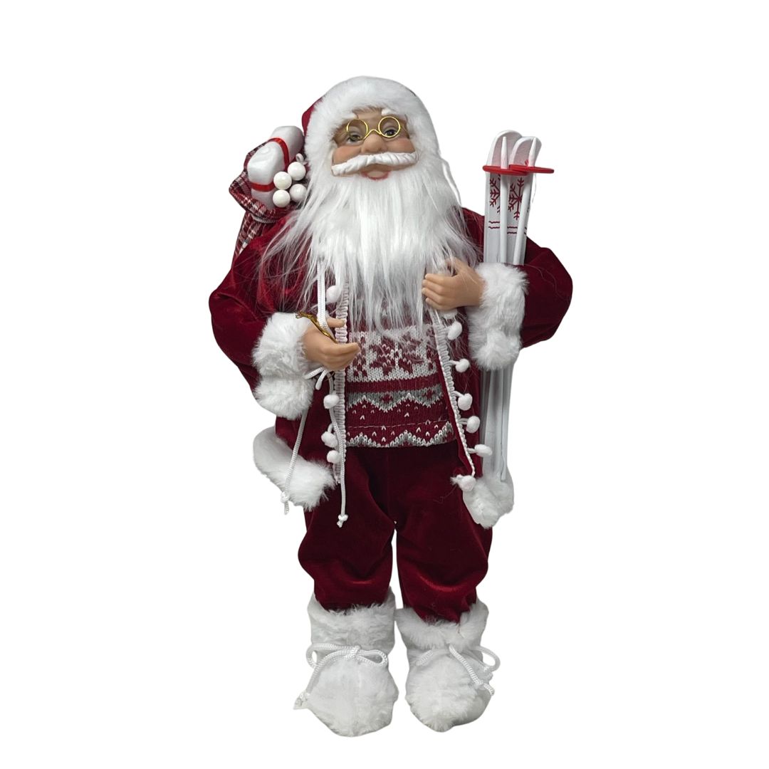 Figura decorativa di Babbo Natale con abito rosso bordato di pelliccia bianca, occhiali dorati, sacco sulle spalle e sci bianchi decorati con fiocchi di neve alto 45cm.