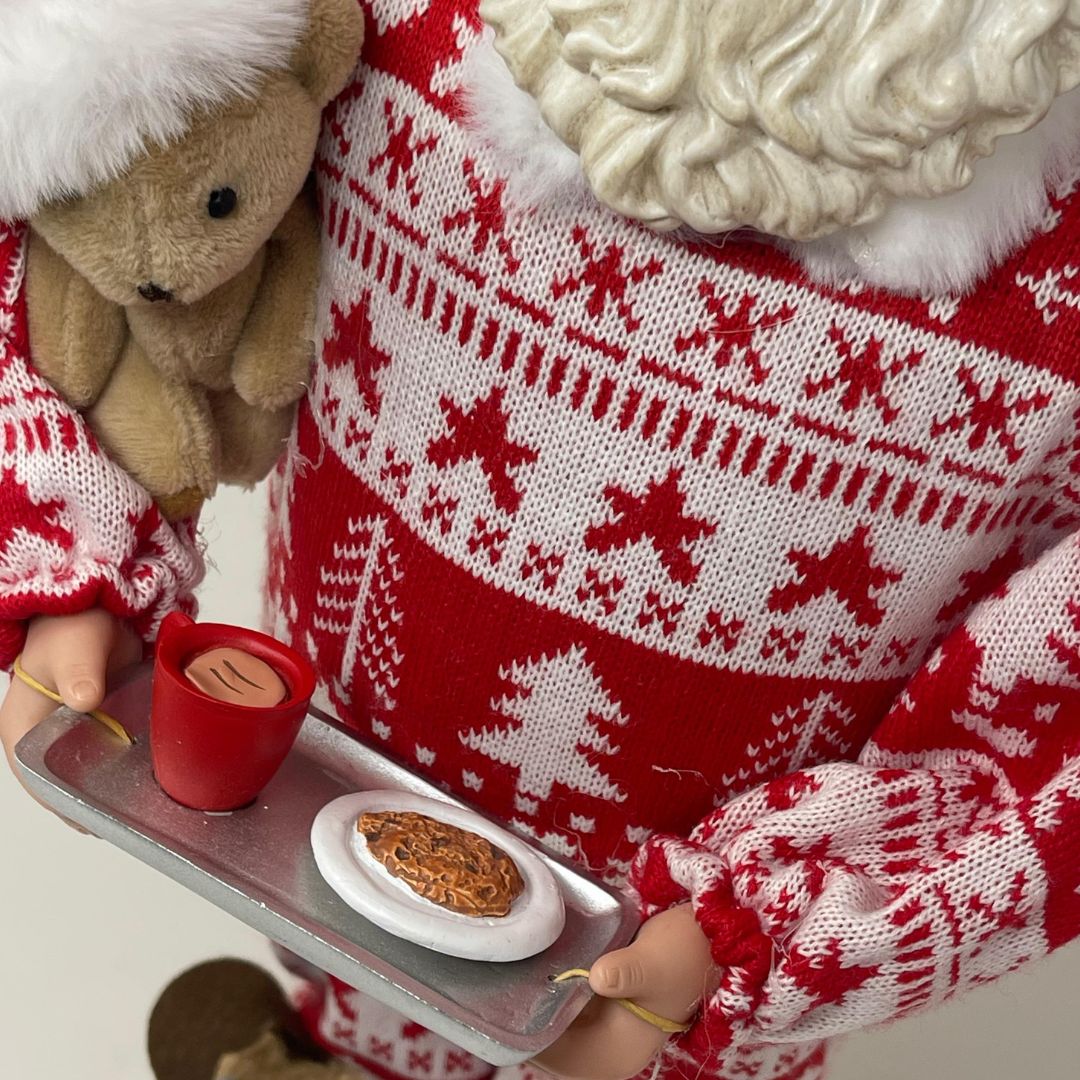 Dettaglio del vassoio di Babbo Natale con pigiama rosso e bianco a motivo natalizio, pantofole renna e orsacchiotto con cappello di Natale in braccio alto 45cm.