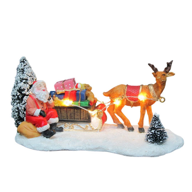 Decorazione natalizia con Babbo Natale seduto accanto alla slitta carica di regali trainata da una renna illuminata a LED su base innevata.