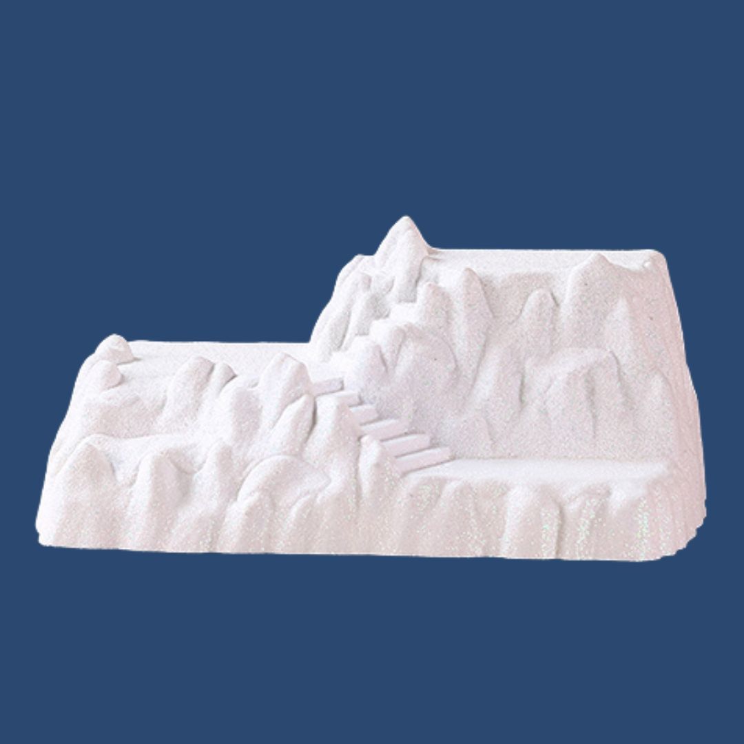 Base decorativa a forma di montagna innevata con scalinate, ideale per allestire villaggi natalizi e paesaggi invernali.