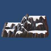 Base decorativa a forma di montagna rocciosa con neve e scalinate, pensata per allestire villaggi natalizi e scenari invernali.