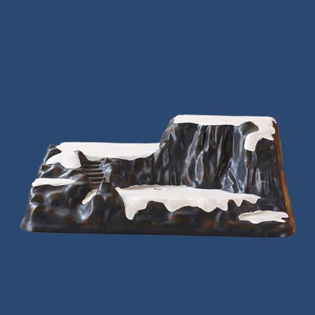 Base decorativa a forma di montagna rocciosa innevata con scalinata, pensata per allestimenti di villaggi natalizi e paesaggi invernali.