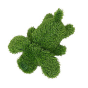 Cane decorativo sdraiato rivestito in prato sintetico verde.