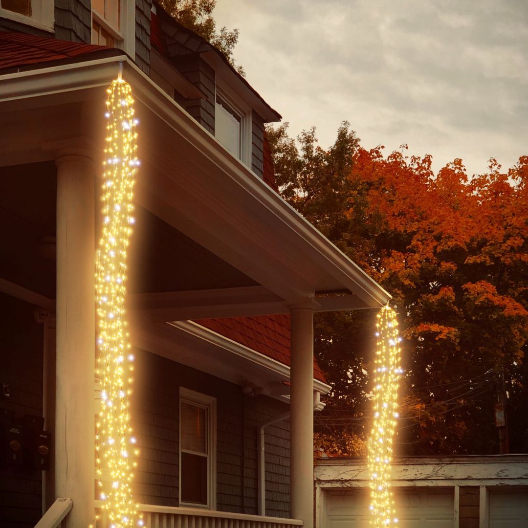 Due fili di cascate 900 micro LED ai bordi di un portico esterno di una casa.