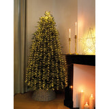 Albero di Natale verde con micro LED bianco caldo in salotto accanto a camino e candele accese.