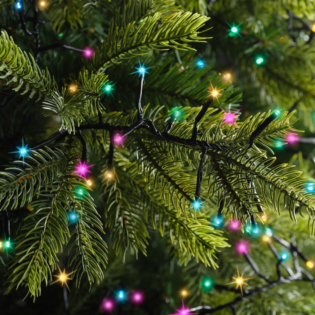 Dettaglio catena luminosa da 1272 micro LED soft multicolor con cavo nero su rami di albero di Natale.