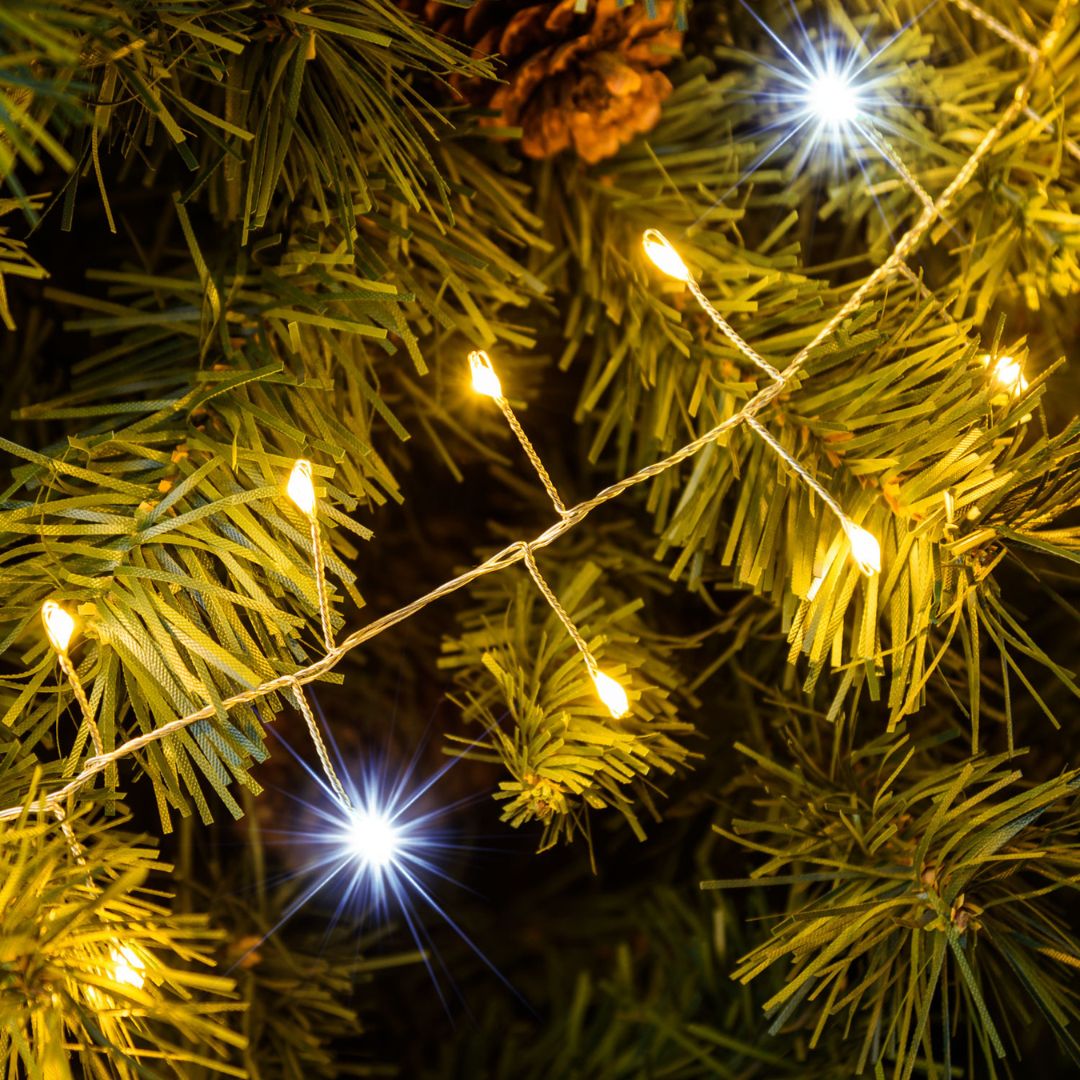 Dettaglio minicluster cavo argento LED bianco caldo con flash LED bianco freddo tra rami di albero di Natale.