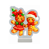 Decorazione luminosa natalizia con coppia di omini di pan di zenzero, uno con cappello di Babbo Natale e l’altra con fiocco rosso e agrifoglio