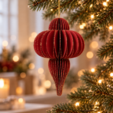 Decorazione natalizia rossa in carta pieghettata appesa all’albero di Natale tra luci calde