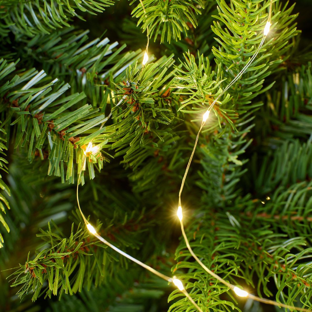 Dettaglio dei rami di un albero di Natale artificiale con filo di micro LED bianco caldo.