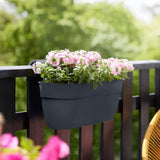 Fioriera da balcone Elho colore antracite con fiori rosa fissata alla ringhiera esterna di un balcone.