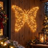 Farfalla luminosa Garden Team da 48 cm con micro LED bianco caldo, appesa a una parete in legno decorata per Natale.
