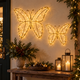 Due farfalle natalizie luminose Garden Team da 32 e 48 cm, con micro LED bianco caldo, appese a una parete decorata.