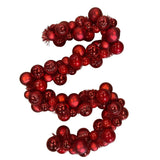 Festone natalizio composto da sfere rosse lucide e opache di diverse dimensioni, unite da un filo decorativo.