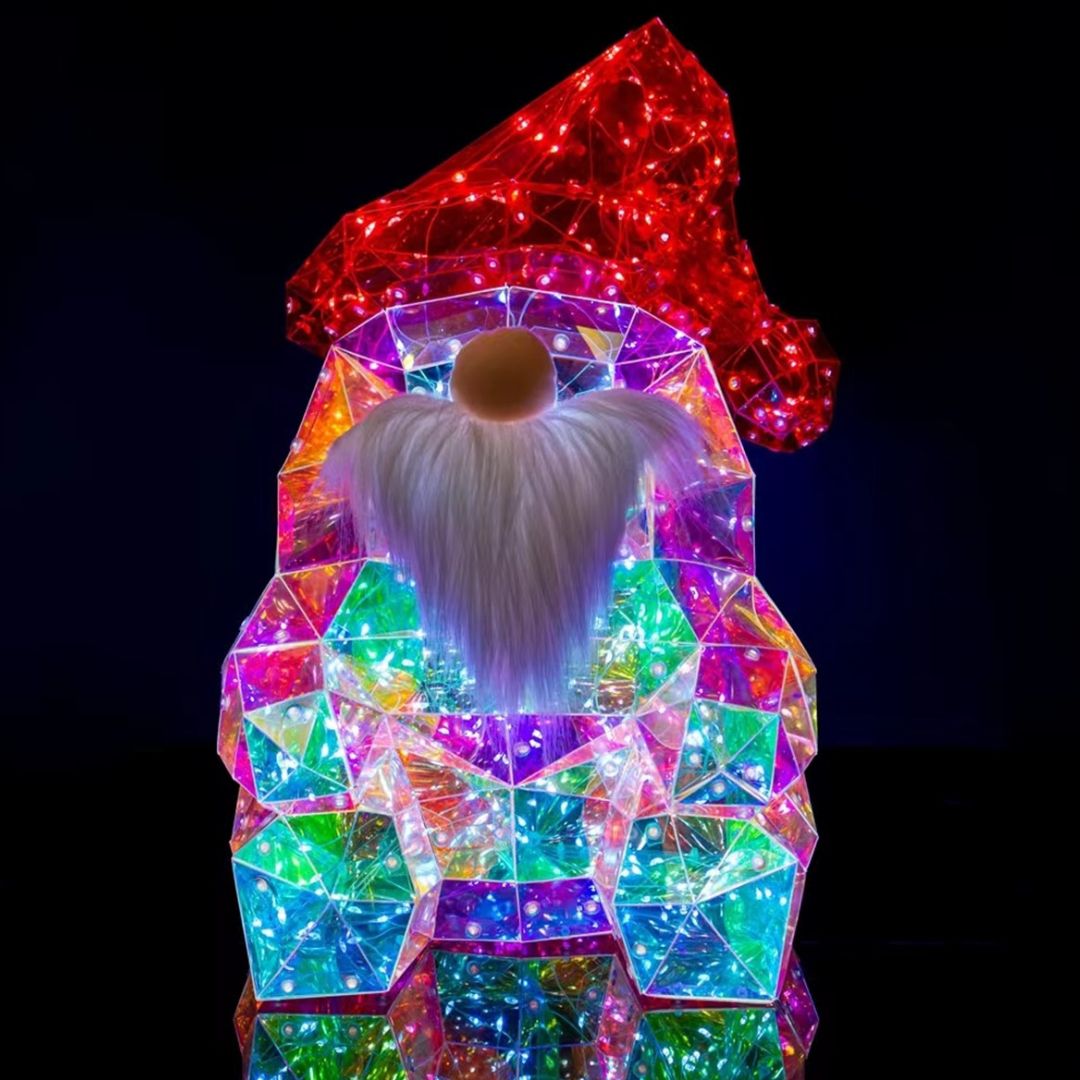 Figura decorativa natalizia a forma di gnomo con cappello rosso luminoso, lunga barba bianca e corpo iridescente composto da superfici trasparenti illuminate da micro LED.