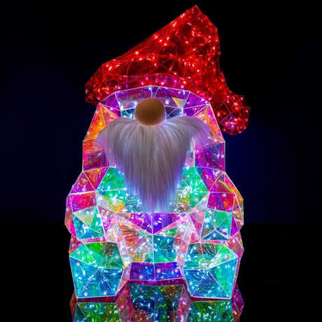 Figura decorativa natalizia a forma di gnomo con cappello rosso luminoso, lunga barba bianca e corpo iridescente composto da superfici trasparenti illuminate da micro LED.