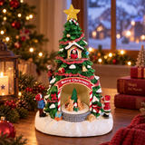 Albero di Natale decorativo con stella, personaggi e orsetti alla base, ambientato su un tavolo con decorazioni natalizie illuminate