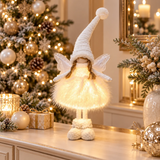 Angelo natalizio bianco illuminato con cappello, ali e abito morbido ambientato tra decorazioni di Natale