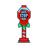 Cartello natalizio luminoso “Santa Stop Here” con luci rosse, bianche e verdi, fiocco e foglie di agrifoglio, su base nera
