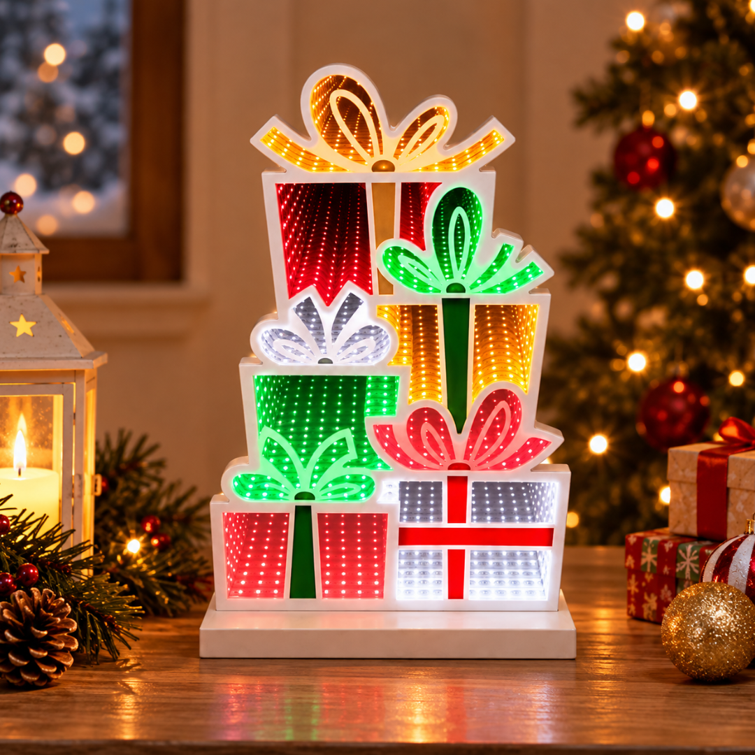 Pacchi regalo natalizi Infinity illuminati in rosso, verde, bianco e oro, ambientati accanto all’albero di Natale