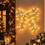 Fiocco natalizio oro da 45 cm con LED bianco caldo appeso alla parete accanto all'ingresso decorato per Natale