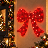Fiocco natalizio rosso da 45 cm con LED rossi appeso alla parete accanto a una porta decorata per Natale