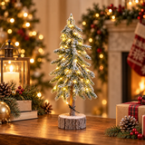 Pinetto natalizio innevato da 50 cm con LED bianco caldo e base in legno, ambientato accanto a regali e decorazioni natalizie.