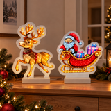 Decorazione luminosa con renna e Babbo Natale sulla slitta, ambientata su un mobile in una casa addobbata per Natale