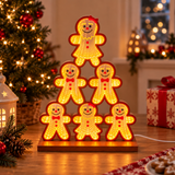 Torre luminosa di omini di pan di zenzero ambientata in una casa addobbata per Natale, accanto all’albero e ai regali