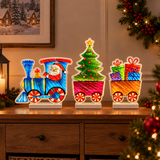 Trenino natalizio luminoso con Babbo Natale, albero e regali, ambientato su un mobile in una casa decorata per Natale