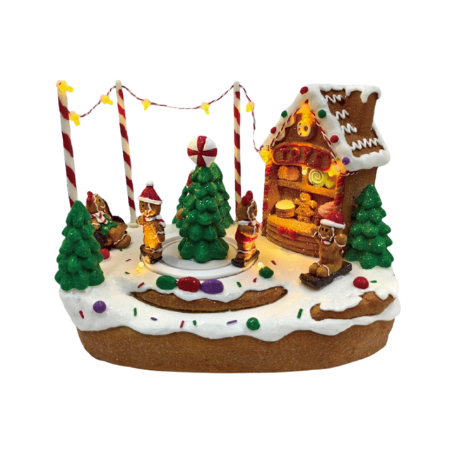Villaggio natalizio a tema pan di zenzero illuminato con casetta, albero decorato, personaggi e dolci su paesaggio innevato